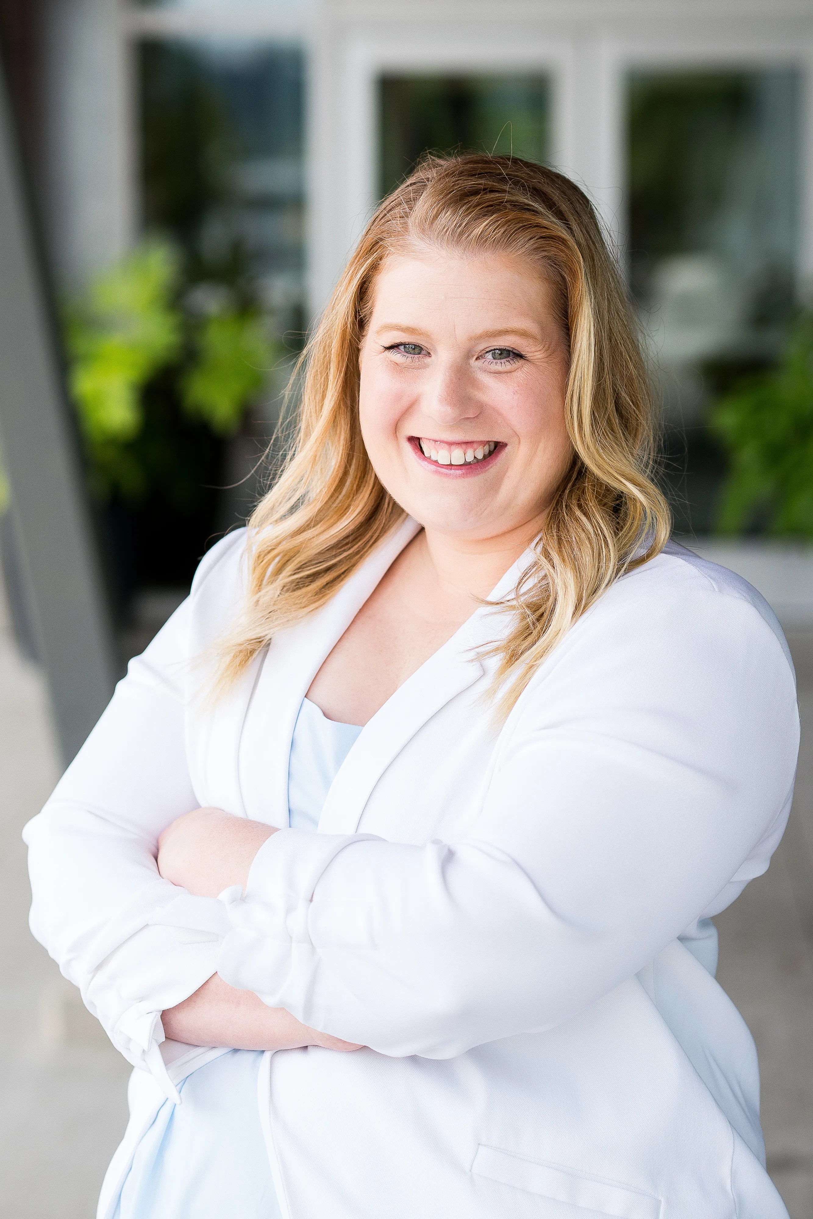 Jessica Morrison, arms crossed with a warm, confident smile, standing outside a modern building.
